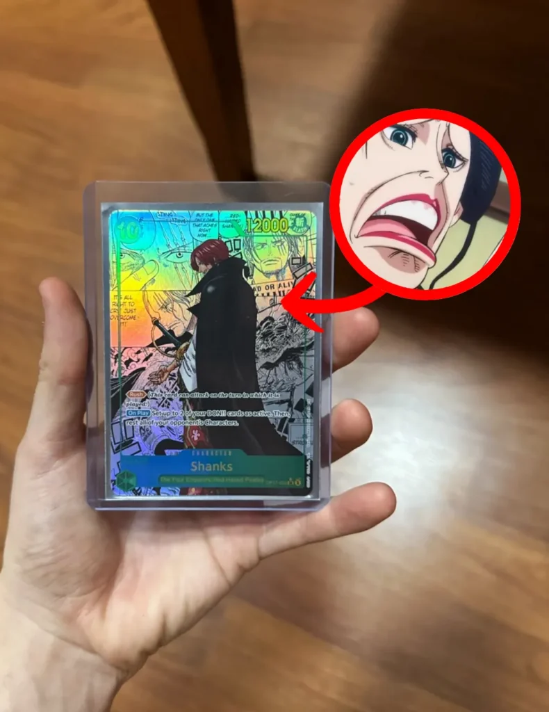 Carta manga de Shanks OP17-022 de One Piece TCG en versión inglesa, en toploader, con la cara de Nico Robin en Wano como reacción
